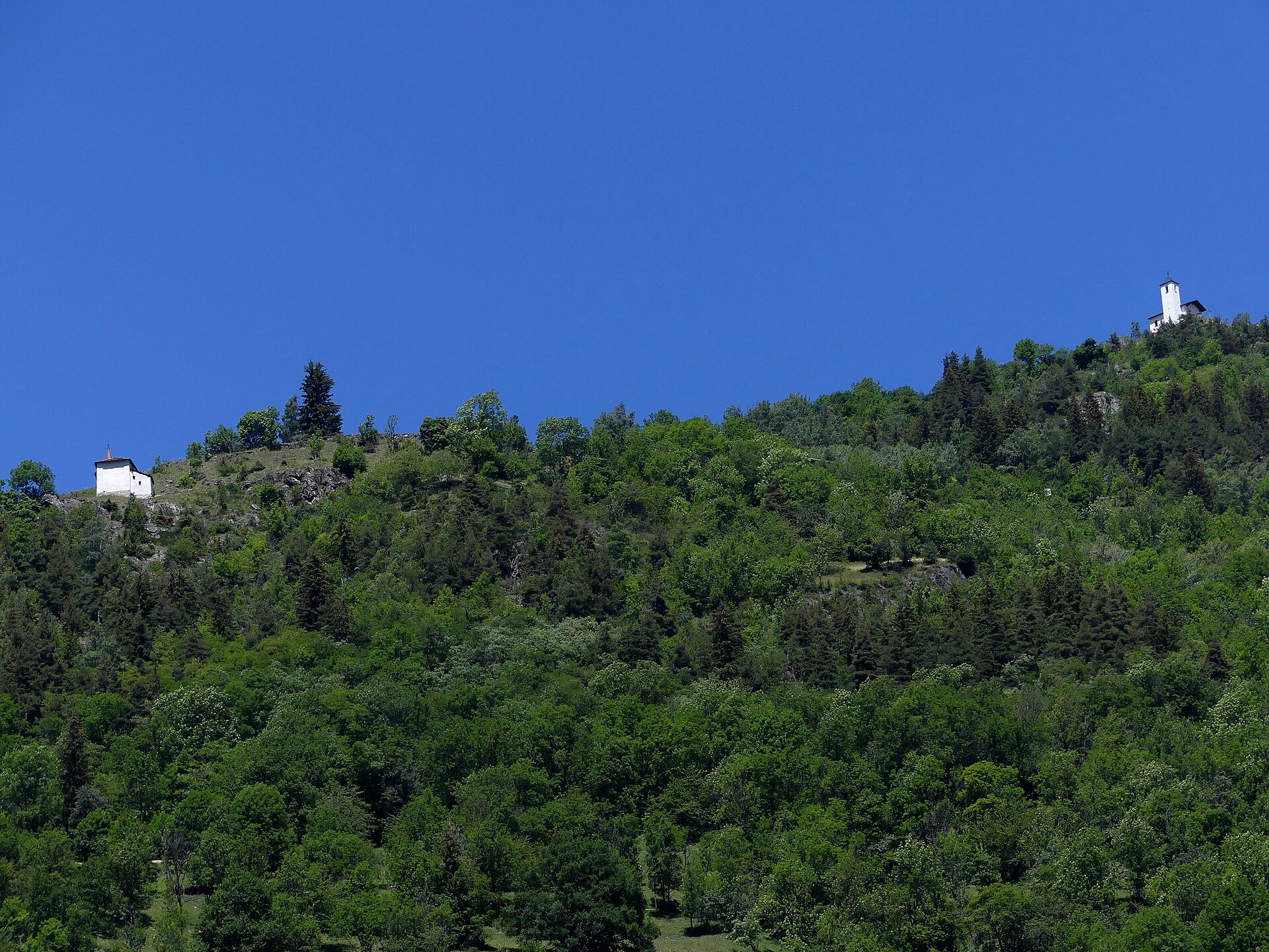 Les chapelles Notre-Dame de Liesse et Saint-Michel perchées sur le versant de Montvalezan, vues depuis la vallée de l'Isère