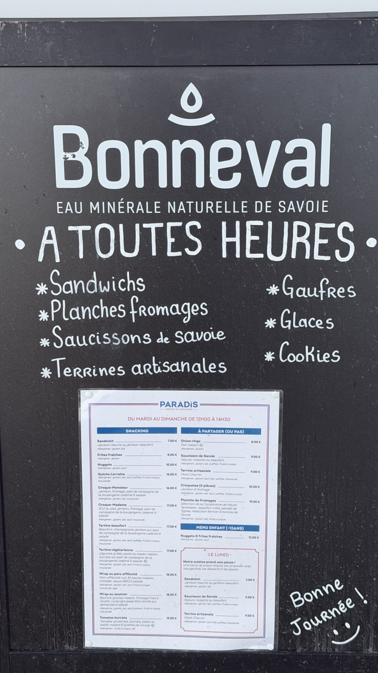 Ardoise du Paradis annonçant sandwichs, planches de fromages et glaces, avec la carte du service de midi affichée