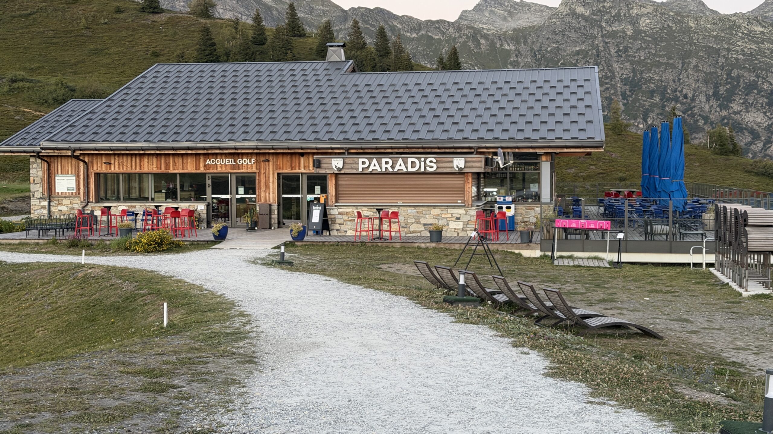 Bâtiment du restaurant Paradis avec sa terrasse, transats et parasols repliés, en fin de soirée