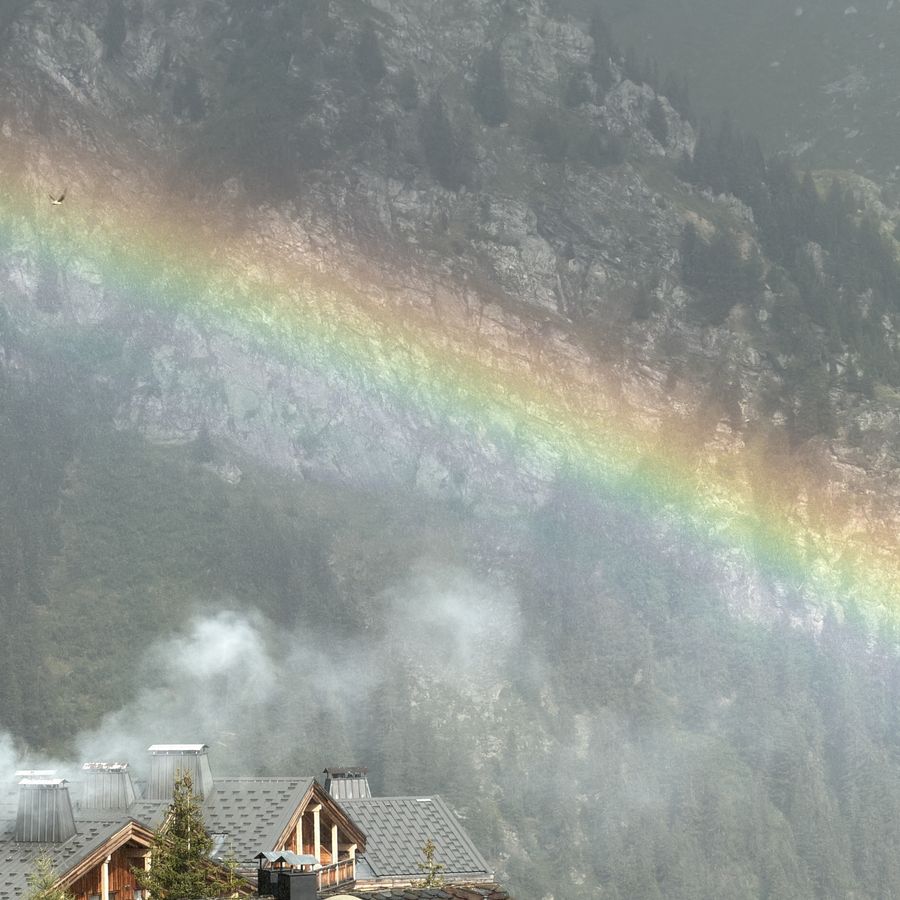 Arc-en-ciel traversant la brume au-dessus des toits de La Rosière