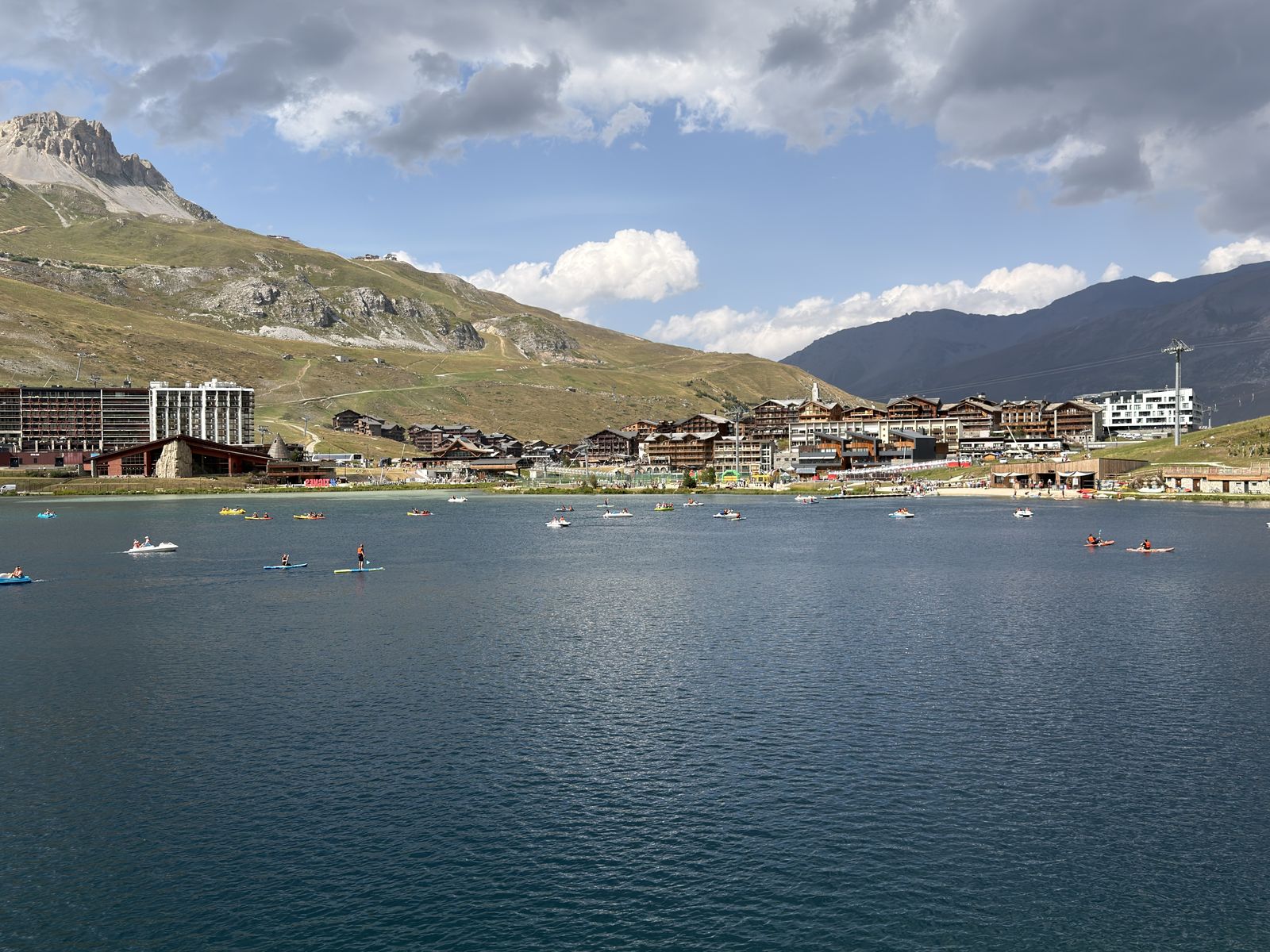 Le lac de Tignes vu depuis la rive, avec la station et les crêtes en arrière-plan